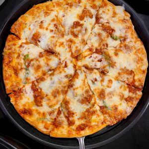 Fresh pizza with melted cheese and toppings in a pan, viewed from above - ideal for food enthusiasts.