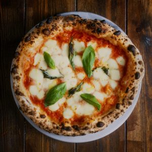 Savory Margherita pizza with fresh basil and mozzarella on a wooden table.