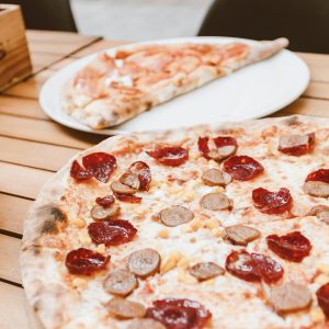 Close-up of pepperoni and sausage pizza on a wooden table, perfect for a tasty meal.