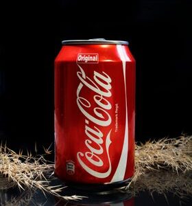 Close-up of a Coca-Cola can on a dark backdrop, emphasizing refreshment.
